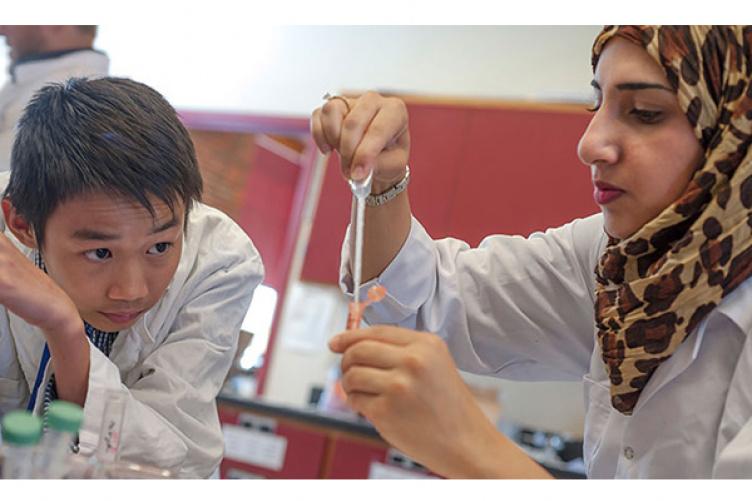 在曼彻斯特大学的夏季EXCELL项目中，来自约旦的生物学助教Zaynav Mahmod协助来自越南的Tan Dao沉淀DNA样本.